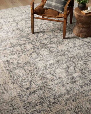 Wooden chair on textured gray area rug in cozy room.