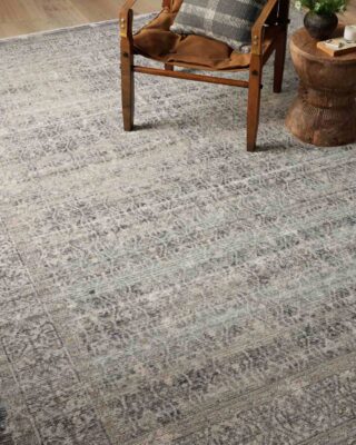 Wooden chair on patterned gray rug in cozy room setting.