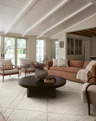 Modern living room with vaulted white ceilings, large windows.