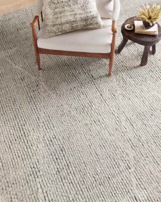 Cozy living room with chair, stool, and shag rug.