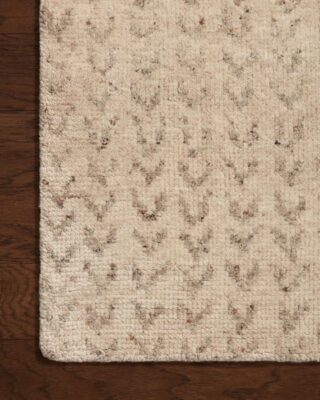 Textured beige floral pattern area rug on wooden floor.