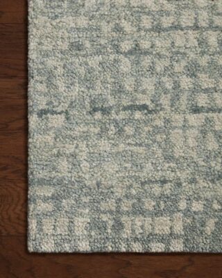 Textured gray and cream patterned rug on wooden floor.