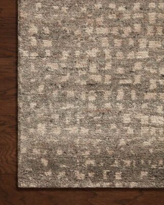 Textured gray and beige patterned area rug on wooden floor.