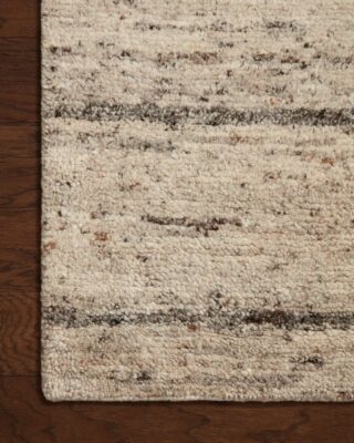 Close-up of textured beige area rug on wooden floor.