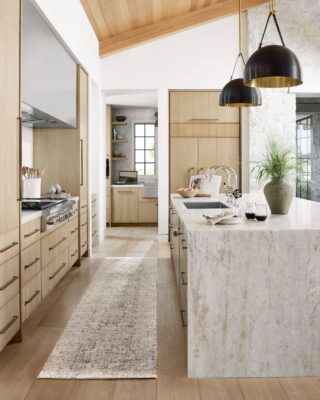 Modern kitchen with wooden cabinets and pendant lights.