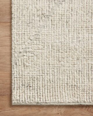 Close-up of a textured white area rug on wood.