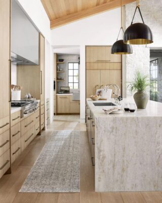 Modern kitchen with wooden cabinets and marble island. Showcasing a Rug from Amber Lewis and Loloi