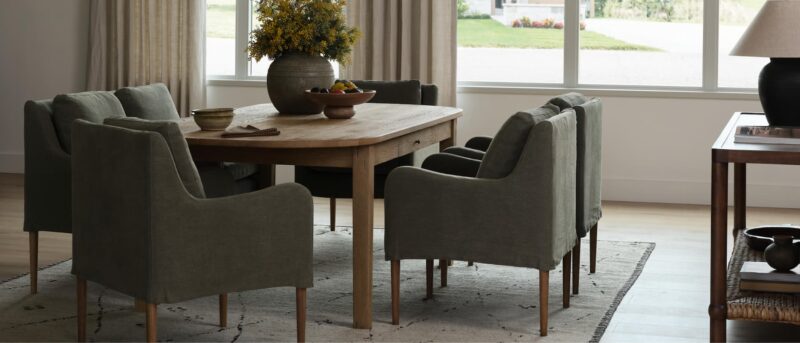 Elegant dining room with rustic wooden table and gray chairs.