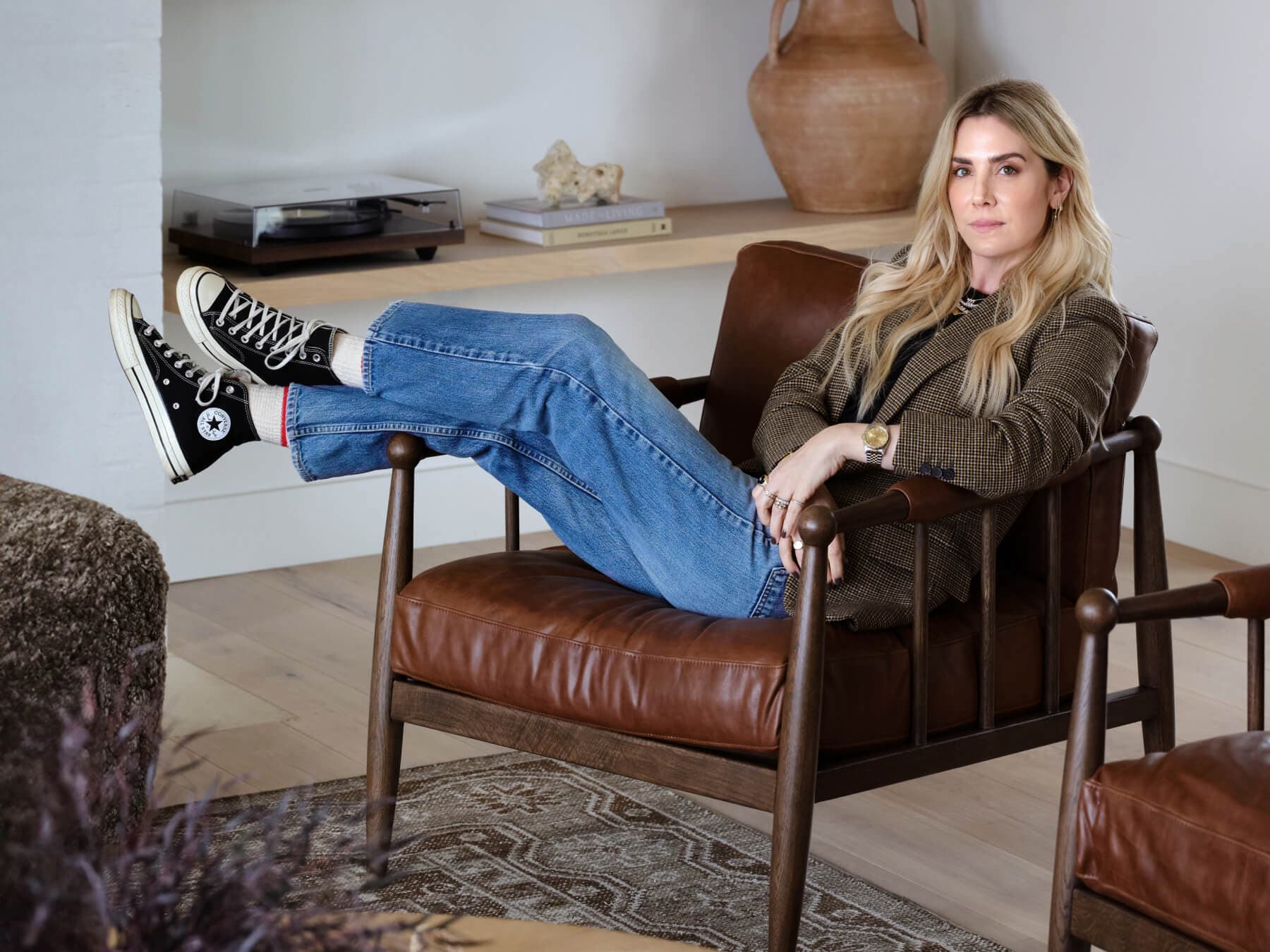 Amber Lewis lounging in chair with sneakers in stylish room.