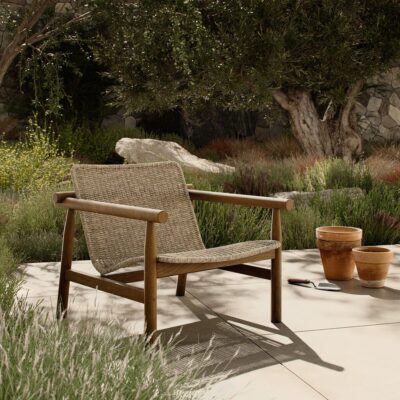 Woven chair in serene garden setting with pots and plants.