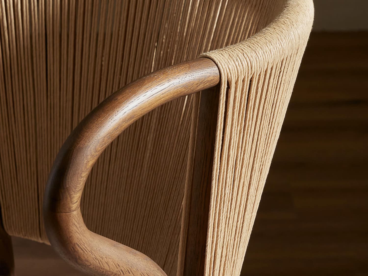 Close-up of textured wooden and rope chair armrest.