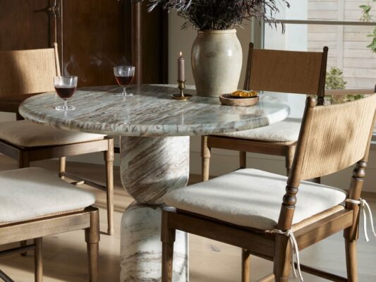 Elegant marble dining table with wooden chairs and wine glasses.